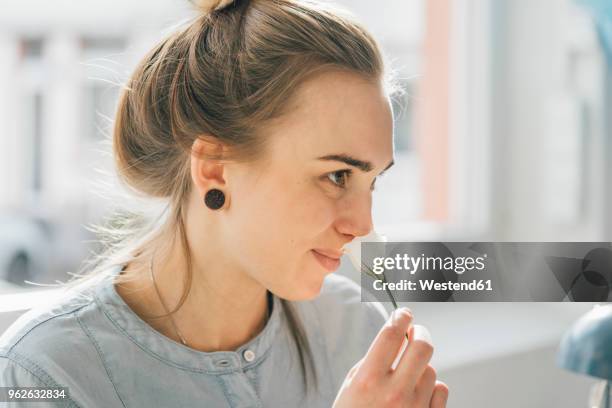 smiling young woman smelling blossom - epitelio nasal fotografías e imágenes de stock