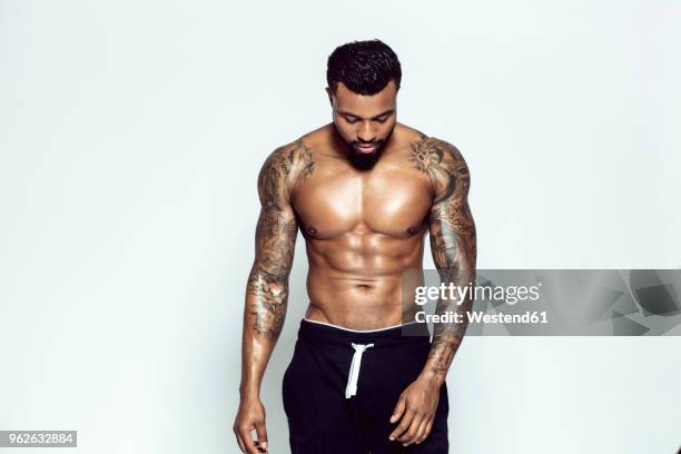 tattooed physical athlete in front of light background - spier stockfoto's en -beelden