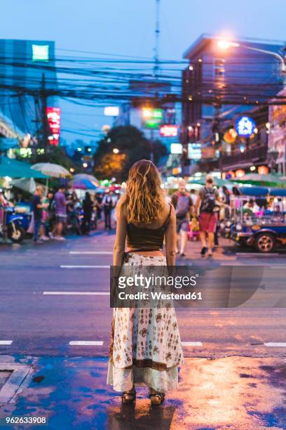 thailand, bangkok, young woman in the city standing on the street at night - bangkok street stock pictures, royalty-free photos & images