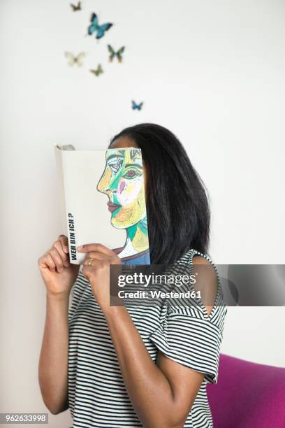 woman covering face with book, reading poetry with butterflies - femme visage caché photos et images de collection