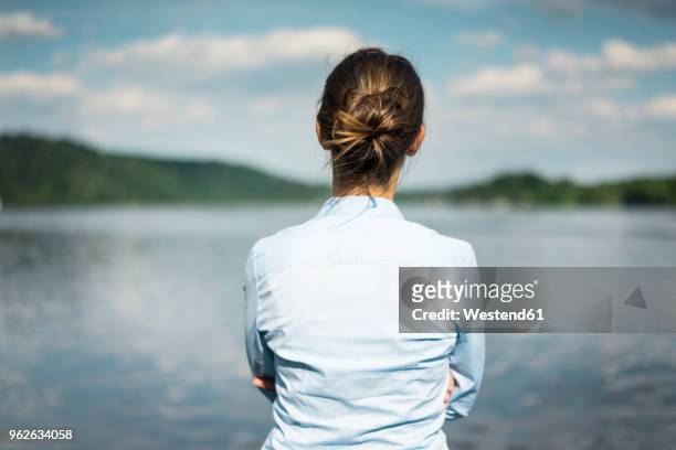 rear view of woman at a lake looking at view - rückansicht stock-fotos und bilder