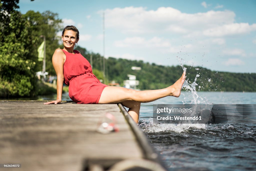 Happy woman sitting on jetty at a lake