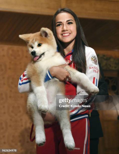 Russian Olympic figure skating champion Alina Zagitova holds an Akita puppy she received from a group preserving the Japanese dog breed, at a...