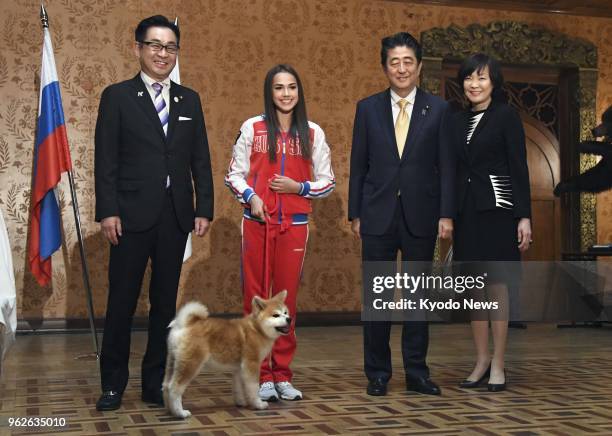 Russian Olympic figure skating champion Alina Zagitova poses beside an Akita puppy she received from a group preserving the Japanese dog breed, at a...