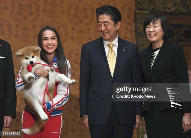 Russian Olympic figure skating champion Alina Zagitova holds an Akita puppy she received from a group preserving the Japanese dog breed, at a...