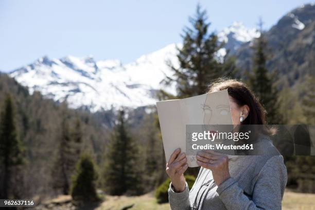 woman covering face with book, reading poetry in the mountains - mystery book stock pictures, royalty-free photos & images