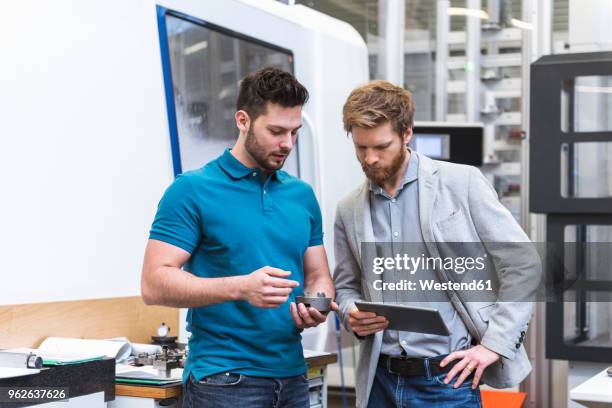 two men with tablet talking in modern factory - tablet 2 personen beratung stock-fotos und bilder