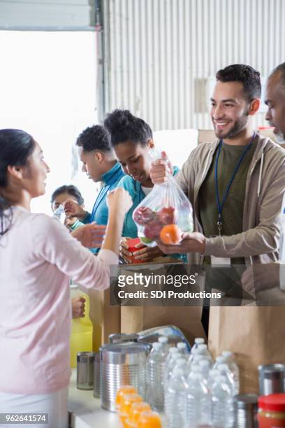 group of food bank volunteers accept and organize donations - homeless shelter man stock pictures, royalty-free photos & images