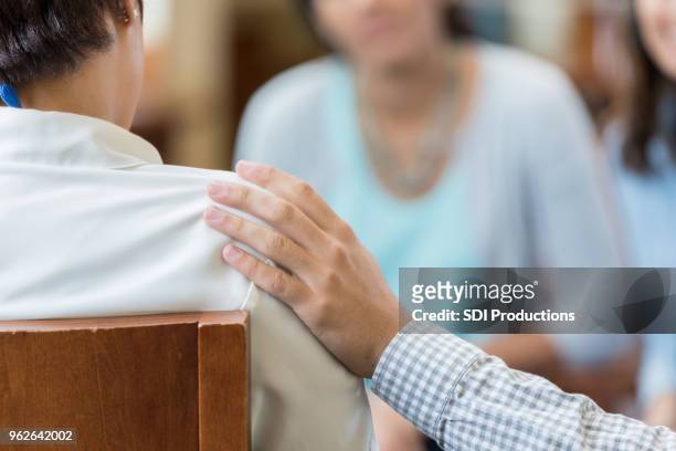 mann komfort frau während der sitzung beratung - gruppe zuhören hilfe stock-fotos und bilder