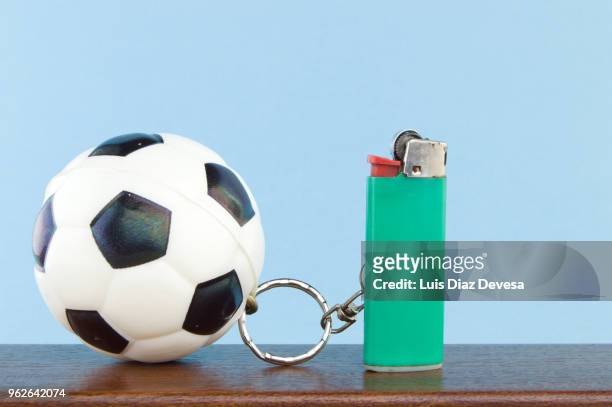 rubber ball football keyring holding green cigarette lighter - green lighter stock pictures, royalty-free photos & images