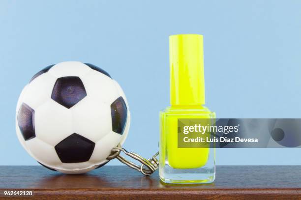 rubber ball football keyring holding  yellow  nail polish - yellow nail polish stock-fotos und bilder