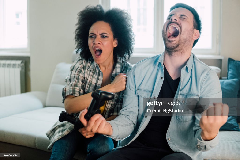 Young couple playing video games, man is excited and woman displeased