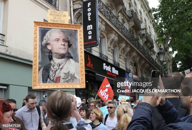 People hold placard depicting French President Emmanuel Macron as a monarch and reading "Restoration of the monarchy" as they take part in a "maree...