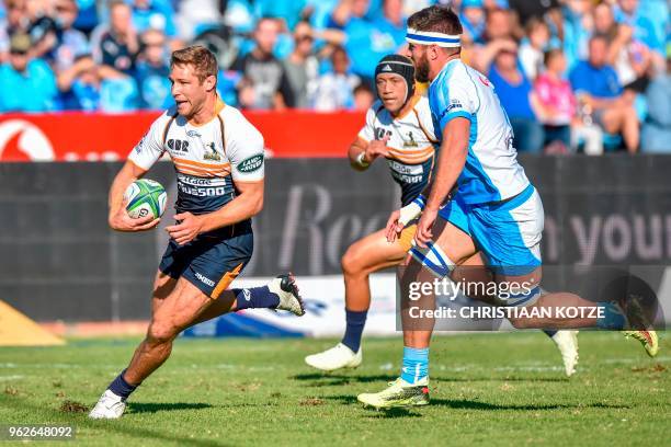 Brumbies' South African center Kyle Godwin runs with the ball as he vies with Bull's players during the SuperRugby rugby match between the Vodacom...