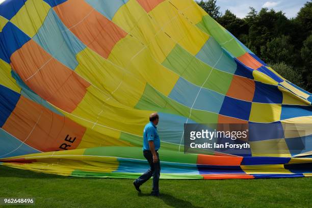Member of the ground crew walks past the partly inflated envelope of a hot air balloon during the Durham Hot Air Balloon Festival on May 26, 2018 in...