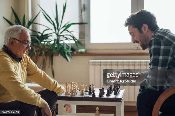 glückliche männer spielen schach - playing chess stock-fotos und bilder