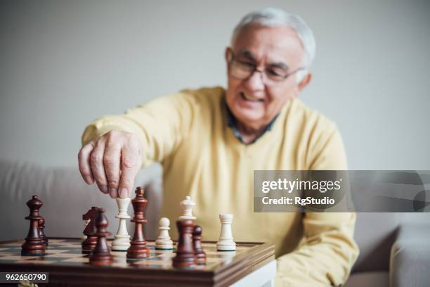 anciano, hacer un movimiento con la pieza de ajedrez - chess fotografías e imágenes de stock