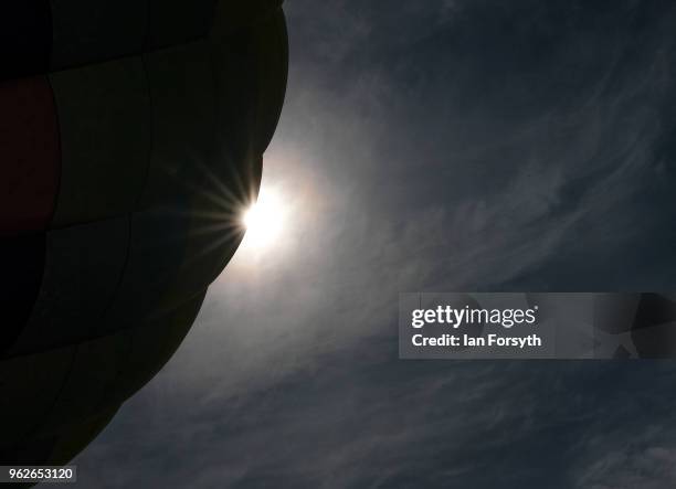 THe sun is seen behind a hot air balloon tethered to the ground after being inflated during the Durham Hot Air Balloon Festival on May 26, 2018 in...