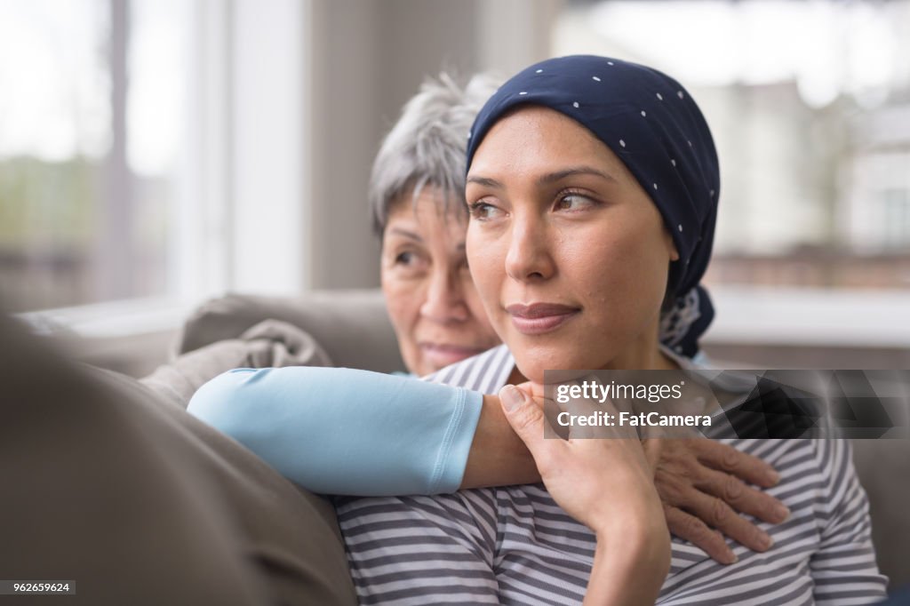 Een Aziatische vrouw in haar jaren 60 omarmt haar mid-30s-dochter die kanker vecht