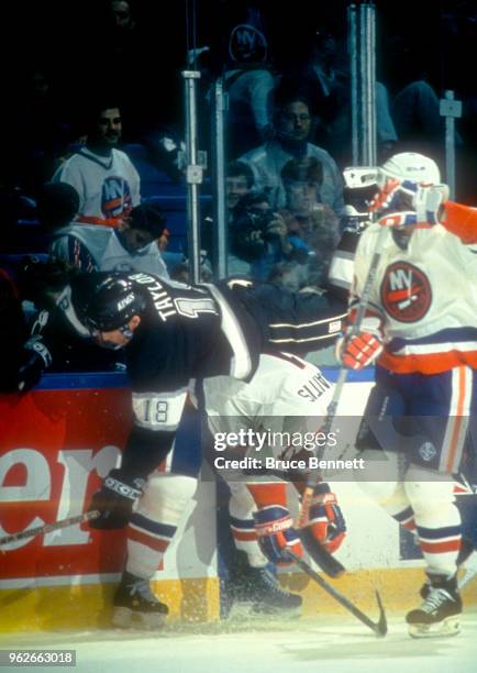 Darius Kasparaitis of the New York Islanders checks Dave Taylor of the Los Angeles Kings during an NHL game circa 1992 at the Nassau Coliseum in...