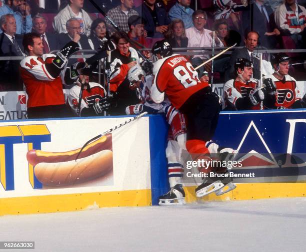 Eric Lindros of the Philadelphia Flyers checks Mark Osborne of the New York Rangers into the Flyers bench during Game 4 of the Conference Semi-Finals...