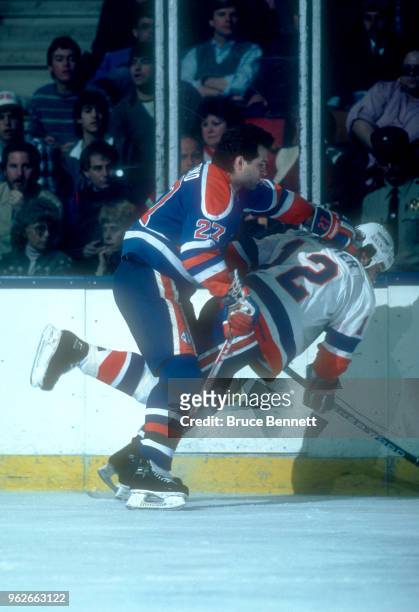 Dave Semenko of the Edmonton Oilers checks Duane Sutter of the New York Islanders during an NHL game circa 1985 at the Nassau Coliseum in Uniondale,...