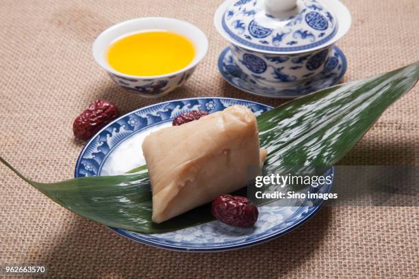 chinese zongzi dumpling on bamboo leaf and tea in cup - bamboo leaf stock pictures, royalty-free photos & images