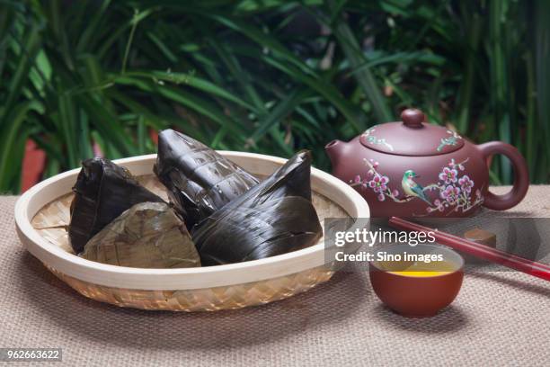 chinese zongzi dumplings wrapped in bamboo leaves, tea cup and teapot - folha de bambu - fotografias e filmes do acervo