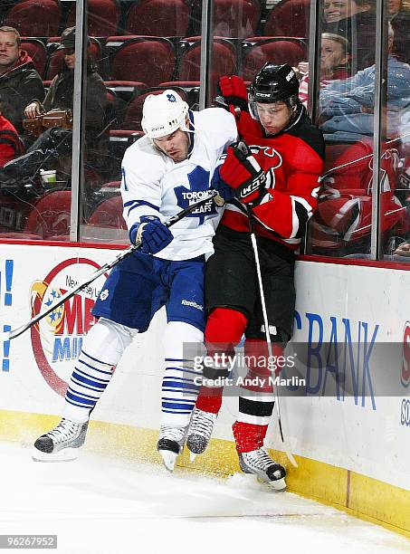 Ian White of the Toronto Maple Leafs and Vladimir Zharkov of the New Jersey Devils come together hard at the boards during their game at the...