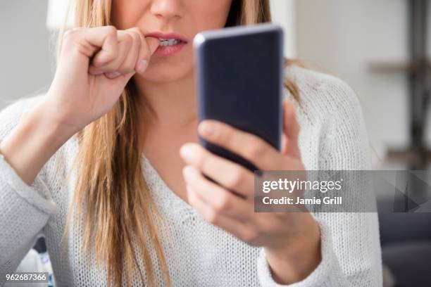 nervous young woman using smart phone - nail biting stock pictures, royalty-free photos & images