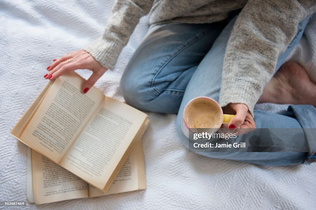 Woman in bed with coffee and book