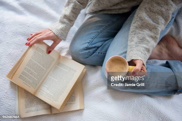 woman in bed with coffee and book - boek stockfoto's en -beelden