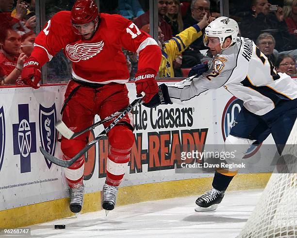 Dan Hamhuis of the Nashville Predators reaches over Patrick Eaves of the Detroit Red Wings to prevent him from getting the loose puck during an NHL...