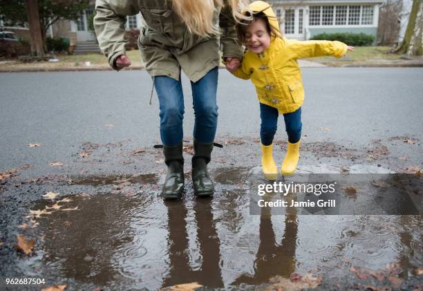 mother and daughter (2-3) near puddle - rain coat stock pictures, royalty-free photos & images