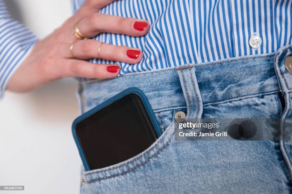 Woman with smartphone in jeans pocket