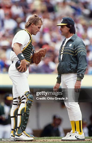 Catcher Jamie Quirk and Manager Tony LaRussa speak confer at home plate during a break in MLB game action circa 1991 in Oakland, California.