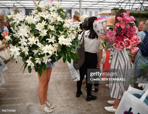 Woman carries a flowers during the 'Great Plant Sale' on the final day of the 2018 Chelsea Flower Show in London on May 26, 2018. - The Chelsea...