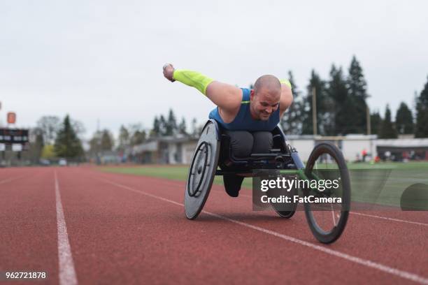 adaptación atleta entrenando en su silla de ruedas de carreras en pista de estadio - carrera de sillas de ruedas fotografías e imágenes de stock