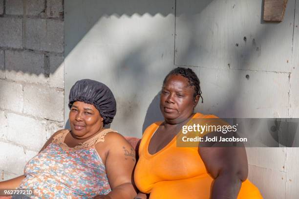 zwei erwachsene kraftstrotzende arme jamaikanischen frauen draußen zu sitzen - jamaican culture stock-fotos und bilder