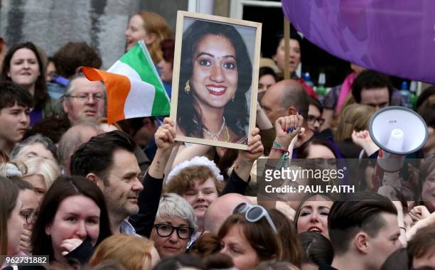 People hold up a portrait of Savita Halappanavar, the Indian dentist who died in Galway because of complications of a miscarriage, at Dublin Castle...