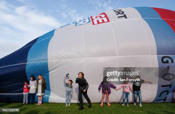 Childrenplay next to a balloon as they are invited onto the field to get closer to the balloons as a decision is made about whether it is safe to fly...