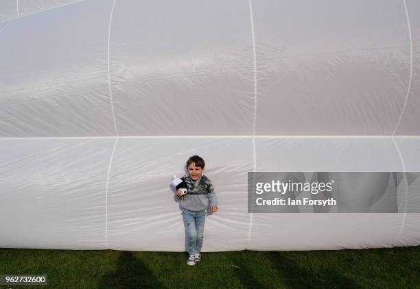 Child stands near a balloon as they are invited onto the field to get closer to the balloons as a decision is made about whether it is safe to fly...