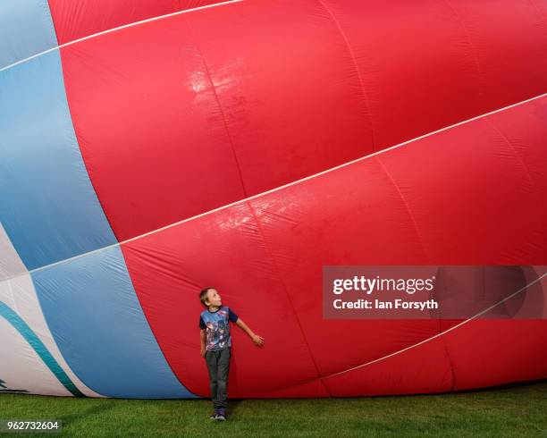 Child stands near a balloon as they are invited onto the field to get closer to the balloons as a decision is made about whether it is safe to fly...