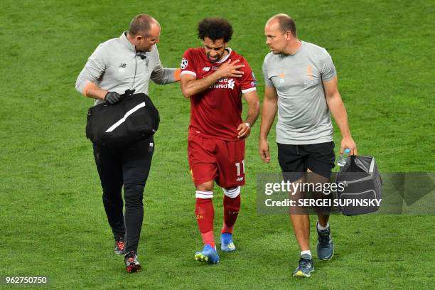 Liverpool's Egyptian forward Mohamed Salah gets medical assistance as he leaves the pitch following injury during the UEFA Champions League final...