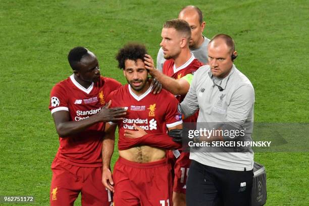 Liverpool's Egyptian forward Mohamed Salah is comforted by team members as he leaves the pitch after injury during the UEFA Champions League final...