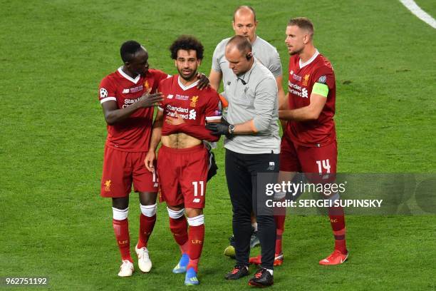 Liverpool's Egyptian forward Mohamed Salah is comforted by team members as he leaves the pitch after injury during the UEFA Champions League final...