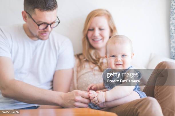 new parents snuggle and play with their baby girl at the table - innocence project stock pictures, royalty-free photos & images