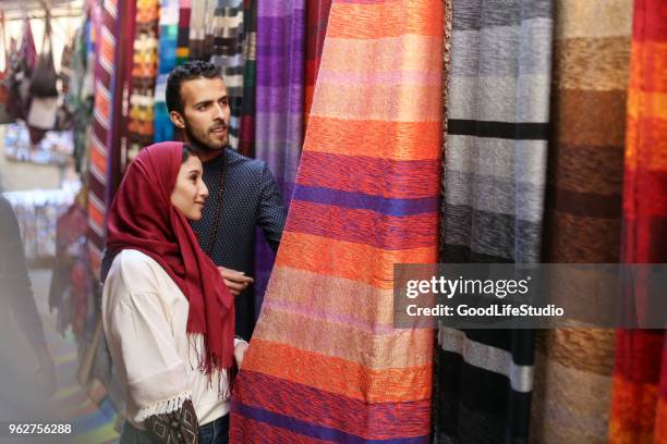 smiling arab couple looking at carpets - middle east clothing stock pictures, royalty-free photos & images