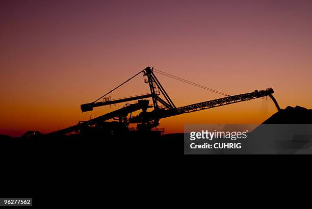 reclaimer against the sunset on a iron ore mine site - mining industry stock pictures, royalty-free photos & images