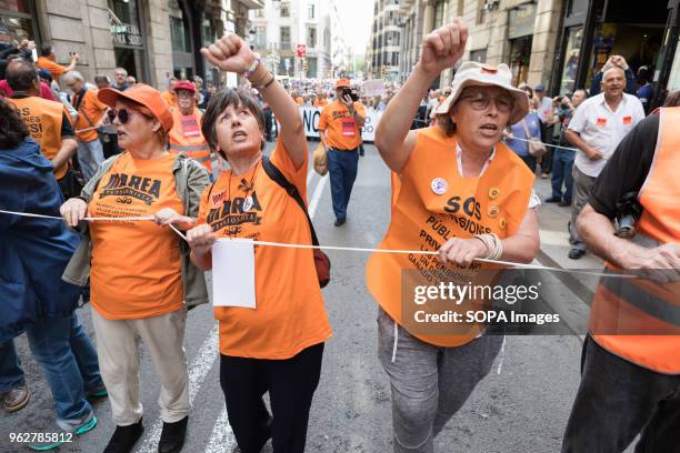 Three woman wearing orange vests rising their fist during the demonstration. Hundreds or people rally in the streets of barcelona claiming for decent...